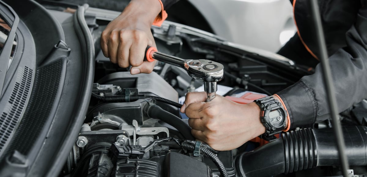Female mechanic working under a car on hydraulic lift