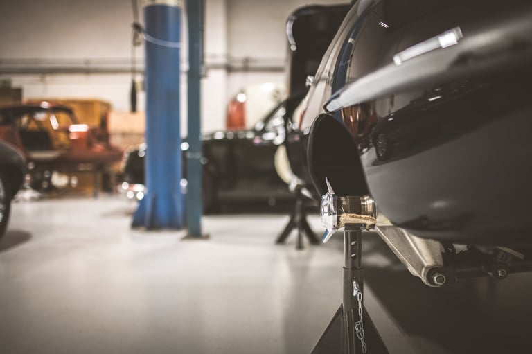 Close-up view of a vintage automobile's rear suspension supported by jack stands in a professional garage setting