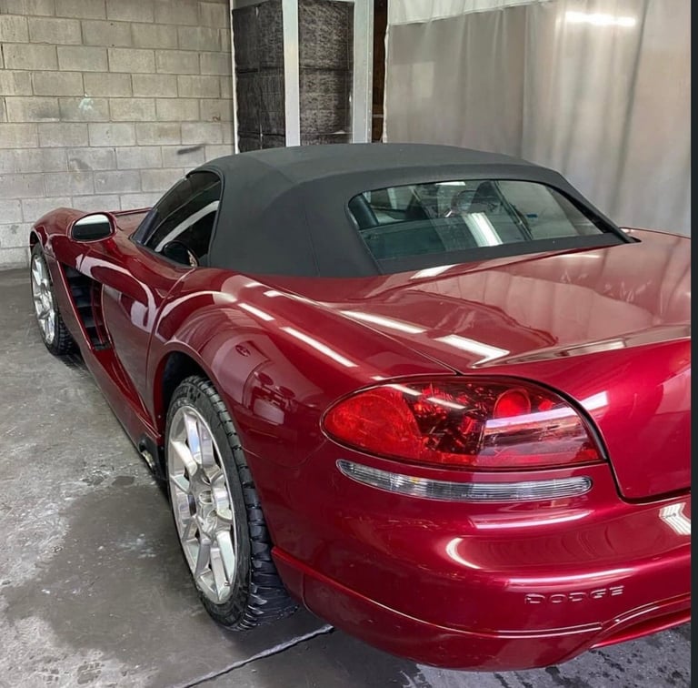 Red convertible sports car with black retractable top parked in a garage